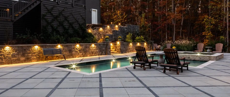 Retaining wall in Cary, NC, by a patio and a pool with outdoor lighting.