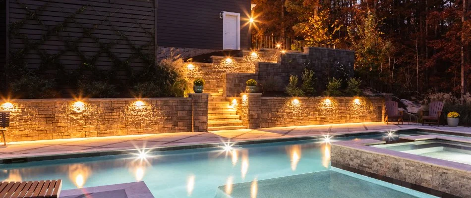 Retaining wall and steps near a pool in Eno, NC, with lighting.