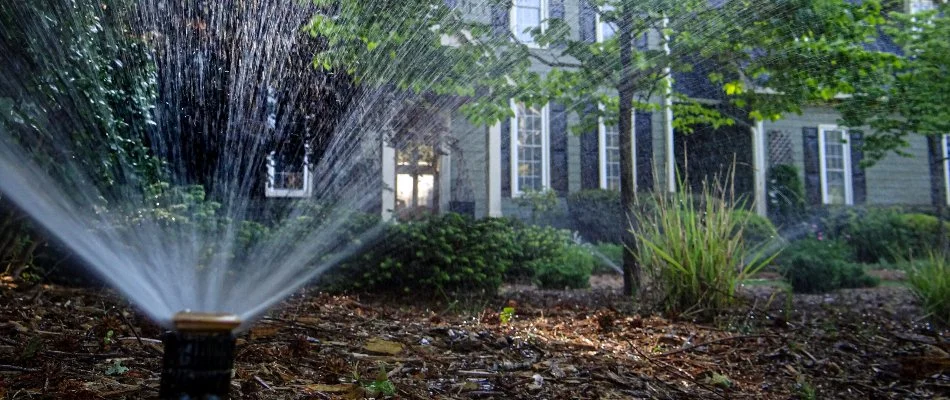 Water spraying from a sprinkler across a landscape bed in Holly Springs, NC.